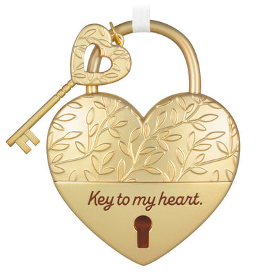 Gold metal heart ornament with leaf-vine design and key, engraved with “Key to my heart” — a romantic gift for newlyweds or partners.