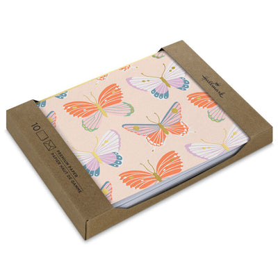 Blank note cards with colorful butterfly illustrations and gold foil accents on a soft peach background.