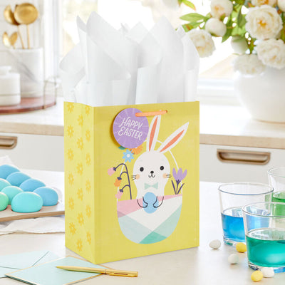 Hallmark Easter gift bag with white bunny in pastel basket on yellow background and floral accents.
