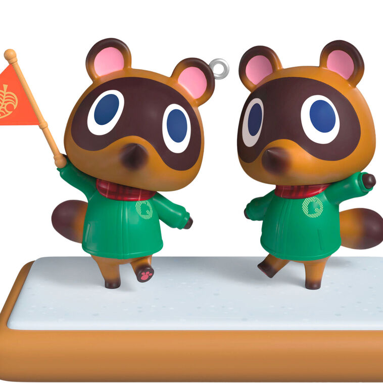 Hallmark Keepsake Nintendo Animal Crossing Timmy and Tommy ornament, twin raccoons with flag, green jackets, red scarves, on wood-style base.