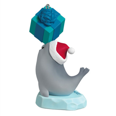 Gray seal ornament in Santa hat balancing gift on nose, sitting on iceberg, year-dated 2025 for grandson Christmas gift

