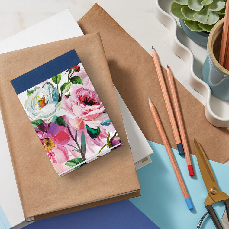 Small list pad with slate blue header and floral fabric cover featuring pink and white blossoms.
