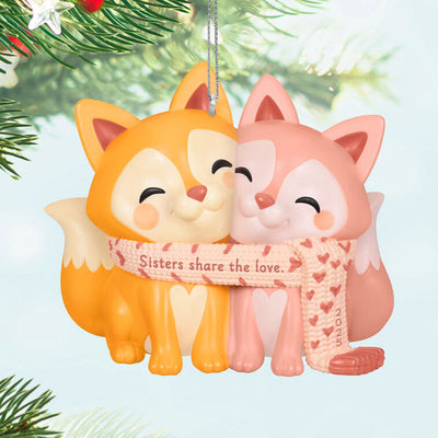2025 Christmas ornament with two foxes snuggled in a heart-patterned scarf, celebrating sisterly love


