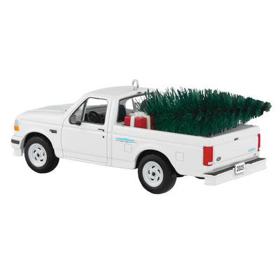White 1995 Ford SVT Lightning truck ornament with turning wheels and a green bottlebrush Christmas tree in the truck bed.