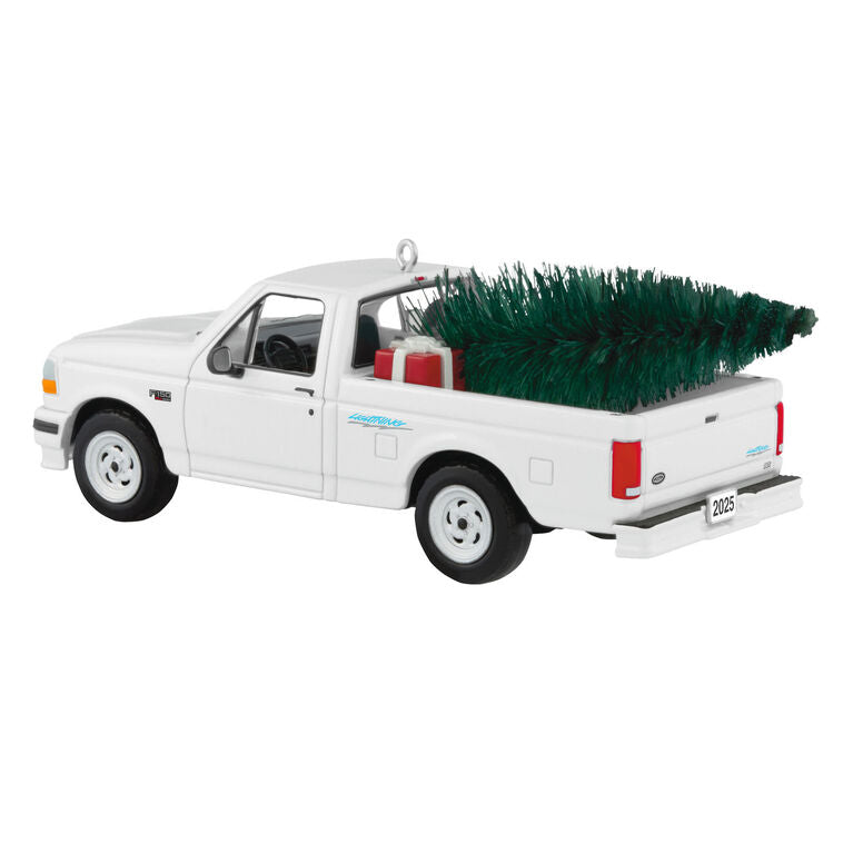 White 1995 Ford SVT Lightning truck ornament with turning wheels and a green bottlebrush Christmas tree in the truck bed.