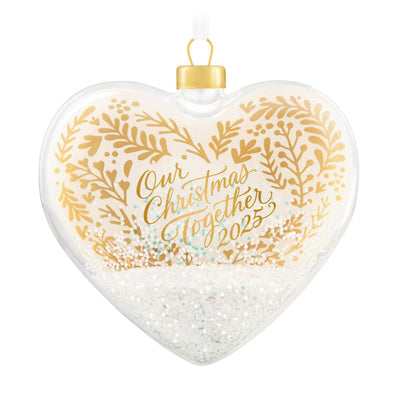 Glass heart Christmas ornament with snow, gold greenery accents, and “Our Christmas Together 2025” message.

