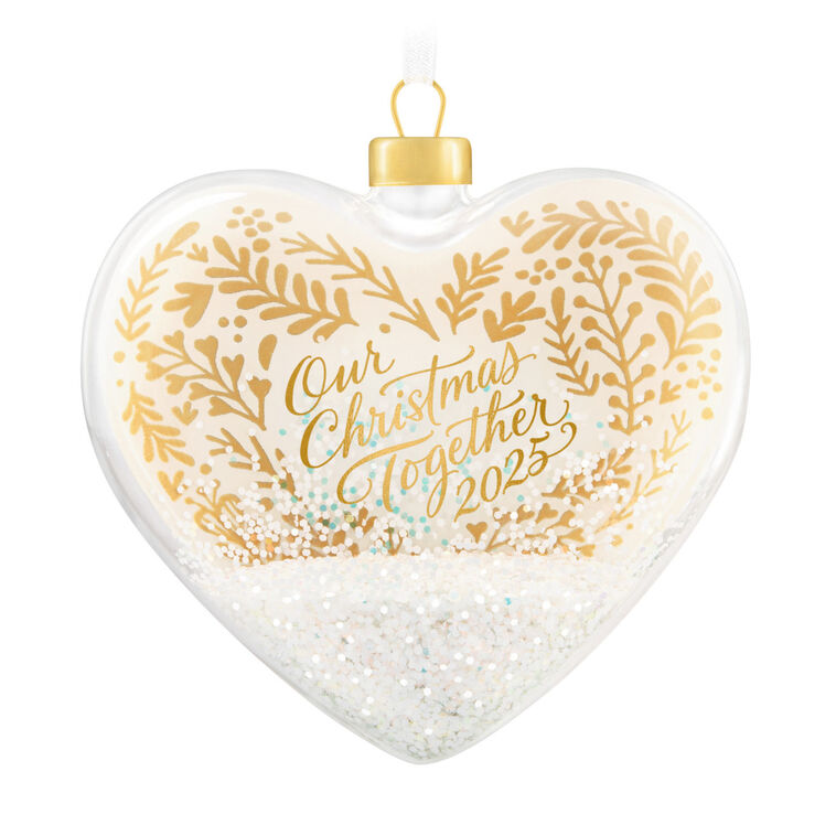 Glass heart Christmas ornament with snow, gold greenery accents, and “Our Christmas Together 2025” message.

