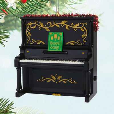 Upright Christmas piano ornament with gold holly accents, tinsel garland, and musical “I’ll Fly Away” gospel choir performa
