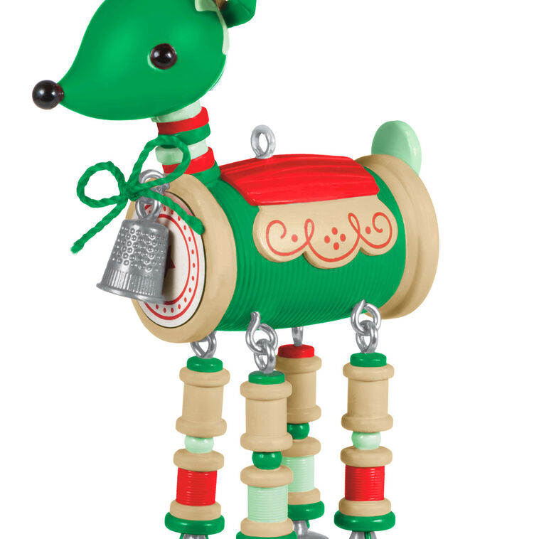 Green reindeer ornament made of red and green thread spools with gold scissors antlers, button tail, and silver thimble bell

