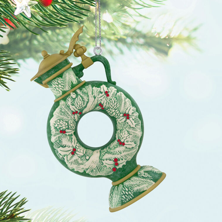 Green beer stein ornament with vintage wreath design, holly, and pinecones; features a gold lid and elegant holiday detailing.