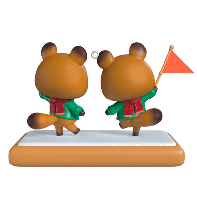 Hallmark Keepsake Nintendo Animal Crossing Timmy and Tommy ornament, twin raccoons with flag, green jackets, red scarves, on wood-style base.