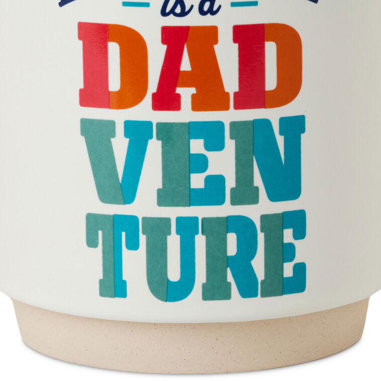 White ceramic mug with colorful "Every day is a Dadventure" lettering, oversized handle, and recessed base for stacking