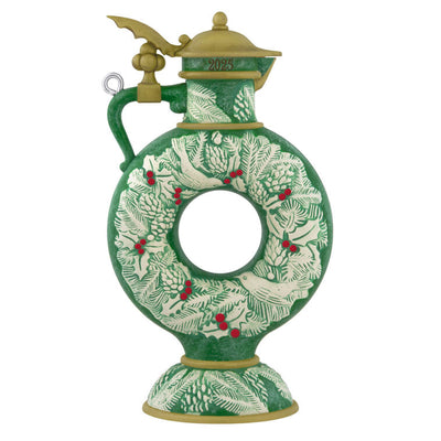 Green beer stein ornament with vintage wreath design, holly, and pinecones; features a gold lid and elegant holiday detailing.