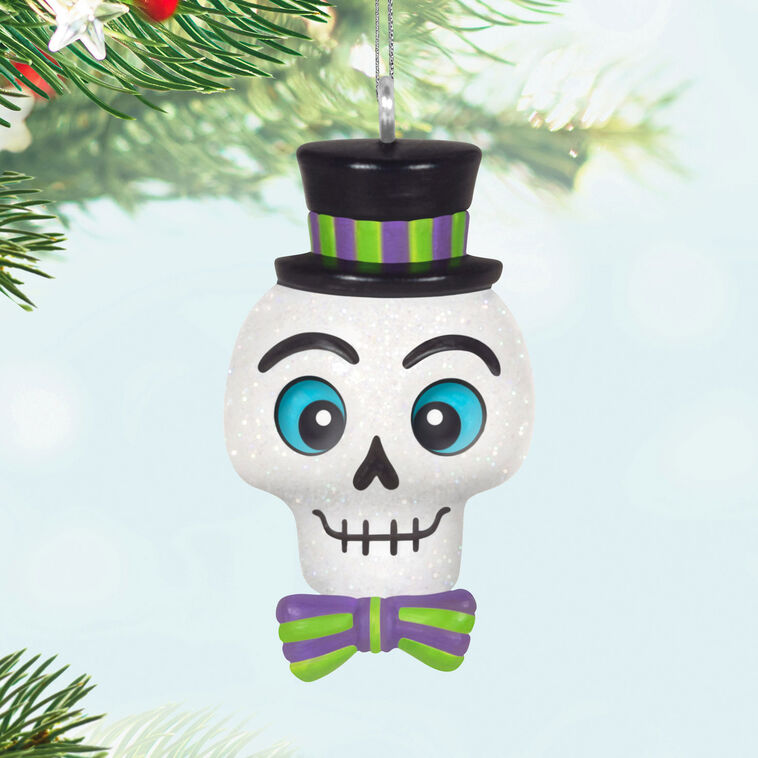 Mini Halloween skull ornament wearing sparkly top hat and bow tie with purple and green accents

