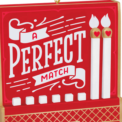 Red and gold matchbook-style ornament with “A Perfect Match” lettering and two heart-accented matchsticks