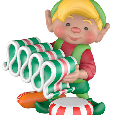 Hallmark Keepsake North Pole Tree Trimmers ornament—Santa’s elf holding old-fashioned ribbon candy, surrounded by hard candies, green hat and red suit
