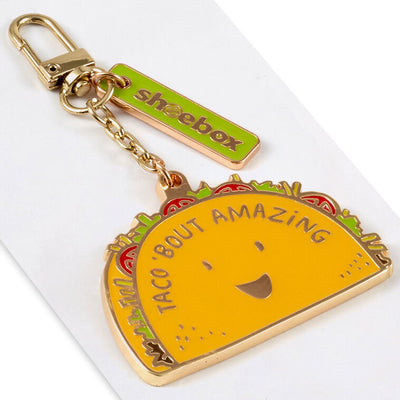 Hallmark taco keychain with smiling yellow taco charm and “Taco 'Bout Amazing” message in white.