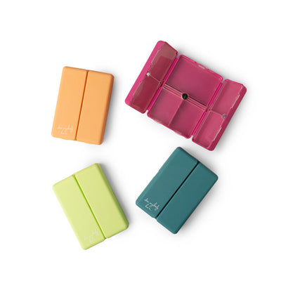 Compact pill and vitamin organizer with seven snap-close compartments and secure magnetic closure, perfect for travel and everyday use.