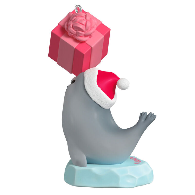 2025 Christmas ornament with gray seal in Santa hat on iceberg, balancing pink present on nose, festive design

