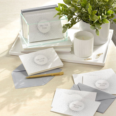 White thank-you cards with silver foil dots radiating from center text and matching envelopes.
