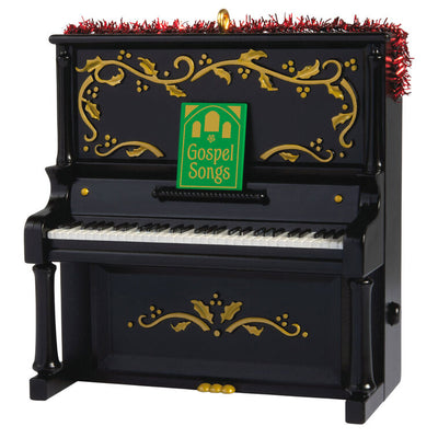 Upright Christmas piano ornament with gold holly accents, tinsel garland, and musical “I’ll Fly Away” gospel choir performa

