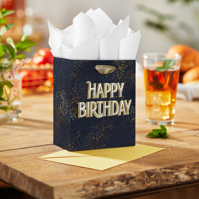 Small Hallmark gift bag with “Happy Birthday” in bold white and gold foil lettering on a navy blue background with gold splatter detail.