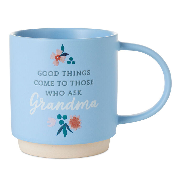 Light blue ceramic mug with “Good things come to those who ask Grandma” text, floral design, and oversized handle.