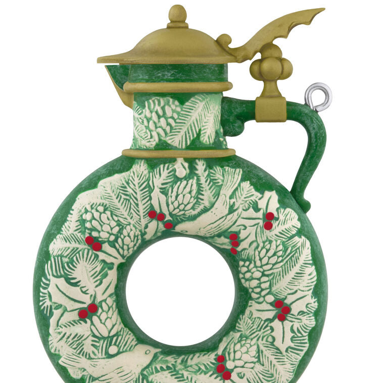 Green beer stein ornament with vintage wreath design, holly, and pinecones; features a gold lid and elegant holiday detailing.