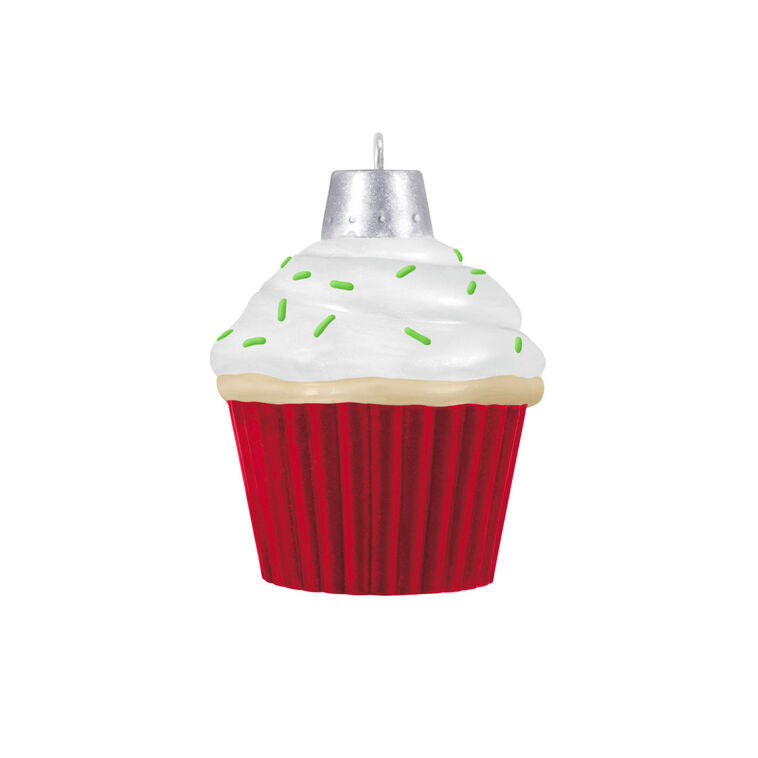 Mini cupcake-shaped ornament with Mrs. Claus waving from a silver-dotted doorway, topped with white icing and green sprinkles.