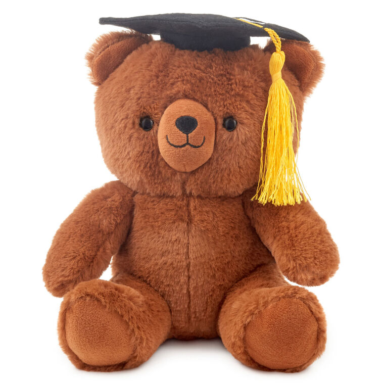 Brown plush teddy bear wearing a black graduation cap with a yellow tassel and embroidered &