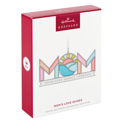 Stained-glass style metal ornament spelling “Mom” with sun and waves in the O, and banner reading “Your love shines through.”