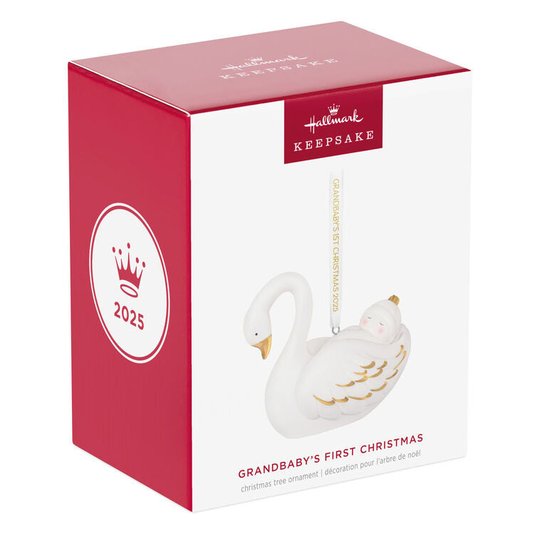 Porcelain Christmas ornament of a baby nestled in a swan’s wings, with gold accents and a commemorative 2025 ribbon

