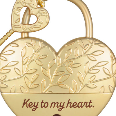 Gold metal heart ornament with leaf-vine design and key, engraved with “Key to my heart” — a romantic gift for newlyweds or partners.