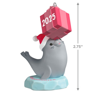 2025 Christmas ornament with gray seal in Santa hat on iceberg, balancing pink present on nose, festive design

