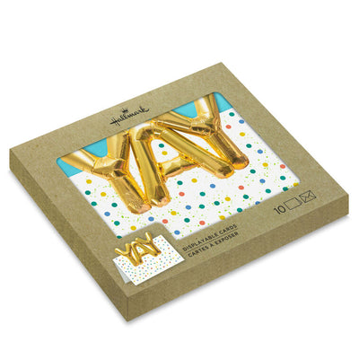 White note cards with gold balloon-style “YAY” lettering, confetti dots, and die-cut front, packaged in kraft wrap.
