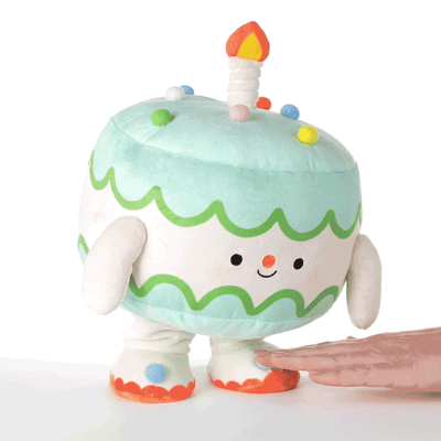 Plush birthday cake toy with smiling face and candle, dances to a fast 'Happy Birthday' song.
