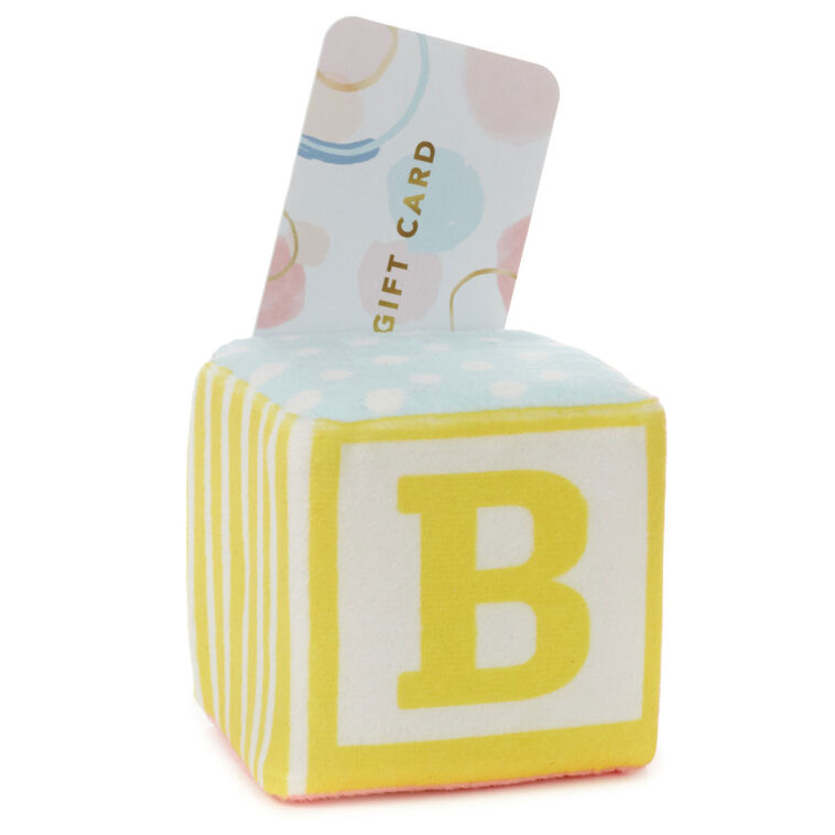 Pastel plush baby block with ABC design and pocket for holding a gift card or mini greeting card, featuring a rattle inside.

