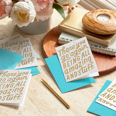 White thank you cards with gold foil block lettering that reads there you go again being all amazing and stuff, includes aqua-lined envelopes