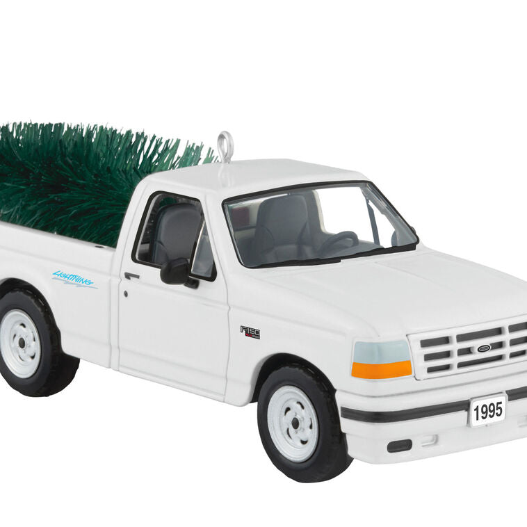 White 1995 Ford SVT Lightning truck ornament with turning wheels and a green bottlebrush Christmas tree in the truck bed.