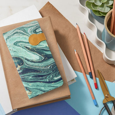 Slim hardcover journal with swirling blue and green marbled cover, gold foil details, and magnetic clasp.

