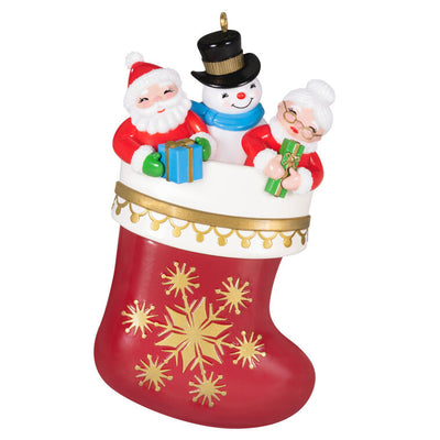 Hallmark Keepsake Stocking Stuffers ornament—red and white stocking with gold snowflakes, Santa, Mrs. Claus, and snowman in vintage style
