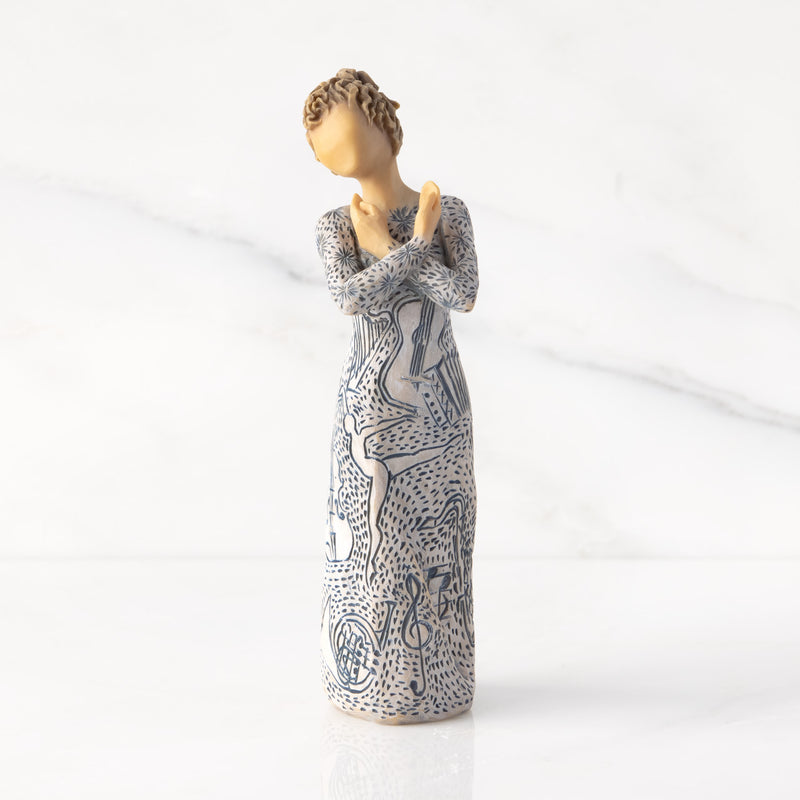 Willow Tree Music Speaks figurine with lighter skin featuring a dress carved with musical symbols and dancing figures.