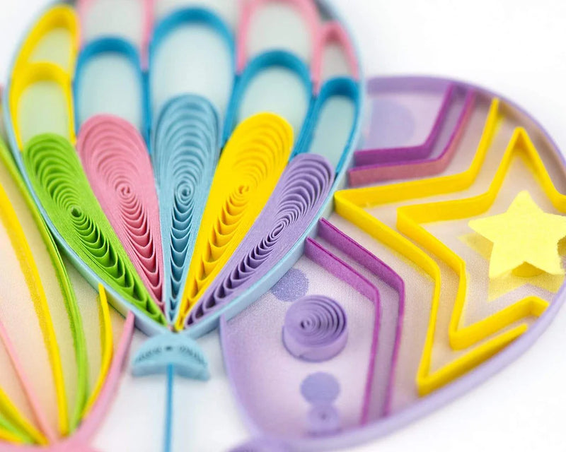 Quilled birthday card with three colorful balloons tied to a gift box with a blue bow and “Happy Birthday” message—playful and festive design.