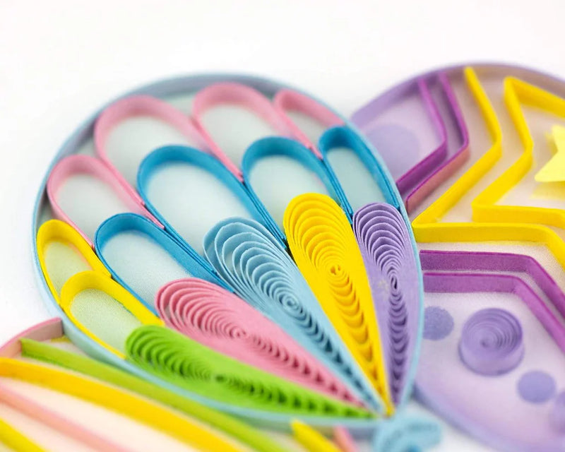 Quilled birthday card with three colorful balloons tied to a gift box with a blue bow and “Happy Birthday” message—playful and festive design.