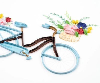 Hand-quilled greeting card featuring a blue bicycle with a flower-filled basket and green border, perfect for cheerful occasions.