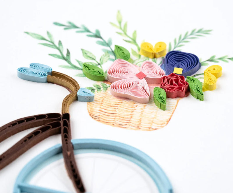 Hand-quilled greeting card featuring a blue bicycle with a flower-filled basket and green border, perfect for cheerful occasions.