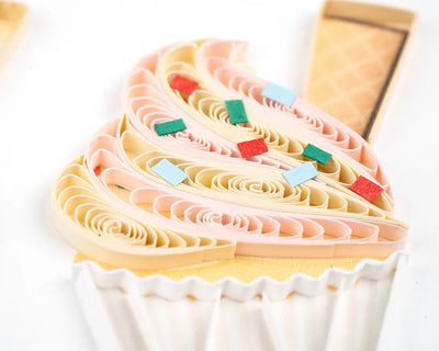 Quilled birthday card with three cupcakes topped in colorful frosting, candy decor, and gold “Happy Birthday” script—fun and festive.