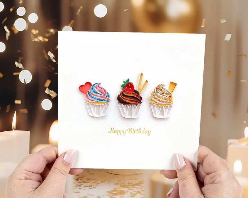 Quilled birthday card with three cupcakes topped in colorful frosting, candy decor, and gold “Happy Birthday” script—fun and festive.