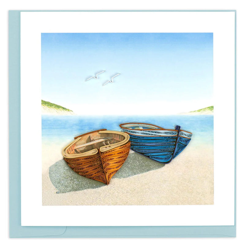 Quilled card with orange and blue canoes resting on a sandy beach, with ocean waves and birds in the background—evoking calm and connection.