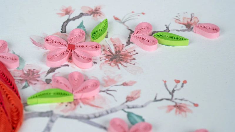 Quilled greeting card featuring a red cardinal perched among delicate pink cherry blossoms on a soft pastel background.